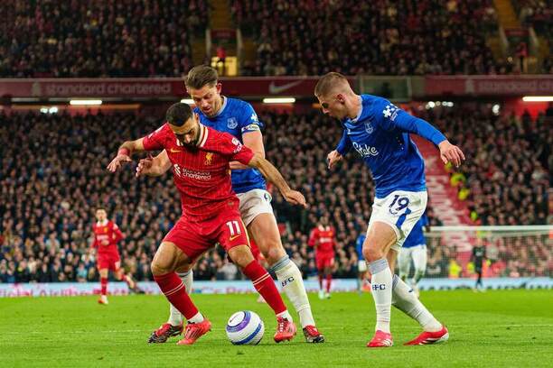 Útočník Liverpoolu Mohamed Salah (v červenom drese) v opatere obrancov Evertonu Jamesa Tarkowskiho a Vitaliya Mykolenka (vpravo) počas posledného vzájomného zápasu Liverpool vs. Everton v sezóne Premier League 2024/25