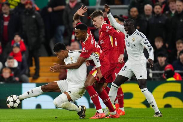 Zľava v súboji o loptu Jude Bellingham (Real Madrid) a Ryan Gravenberch (Liverpool) pod dohľadom ich spoluhráčov počas zápasu Liverpool vs. Real Madrid v 5. kole ligovej fázy Ligy majstrov UEFA 2024/2025